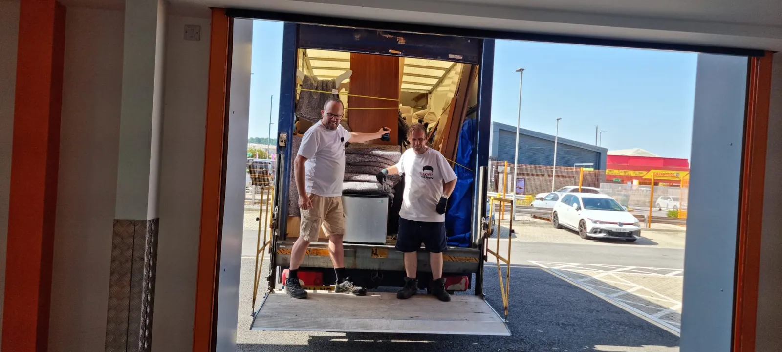 Two-man crew loading a fridge and furniture at a retail unit